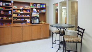 Una kitchenette con cafetera, una mesita y sillas.
