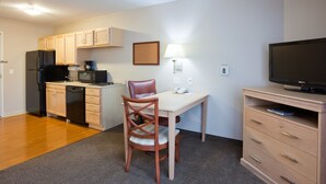 A compact kitchen with a refrigerator, microwave, and coffee maker. There is a dining table with a chair and a TV on a stand. - Candlewood Suites Milwaukee Brown Deer by IHG (Milwaukee)