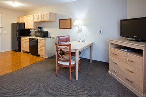 A compact kitchen with a refrigerator, microwave, and coffee maker. There is a dining table with a chair and a TV on a stand. - Candlewood Suites Milwaukee Brown Deer by IHG (Milwaukee)