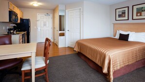 A hotel room with a bed, a desk with a chair, a microwave, and a refrigerator. - Candlewood Suites Milwaukee Brown Deer by IHG (Milwaukee)