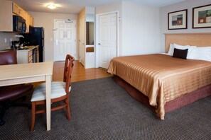 A hotel room with a bed, a desk with a chair, a microwave, and a refrigerator. - Candlewood Suites Milwaukee Brown Deer by IHG (Milwaukee)