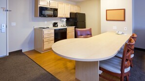A compact kitchen with a dining area, featuring a microwave, refrigerator, and a small sink. - Candlewood Suites Milwaukee Brown Deer by IHG (Milwaukee)