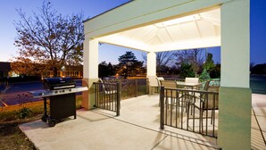 Un área de patio al aire libre con una parrilla, asientos y una sección cubierta.