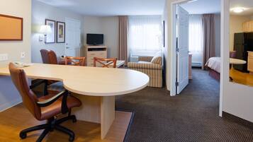 Una habitación de hotel con comedor, televisión, cama y kitchenette.
