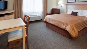 A hotel room with a bed, a desk, a chair, a television, and an air conditioning unit. - Candlewood Suites Milwaukee Brown Deer by IHG (Milwaukee)