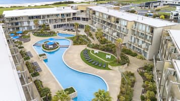 A resort with a swimming pool, sun loungers, and a view of the ocean.