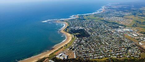 Vista aérea de un pueblo costero con playa, zonas residenciales y una combinación de edificios comerciales.
