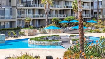 A hotel with a swimming pool, outdoor seating, and a landscaped garden.