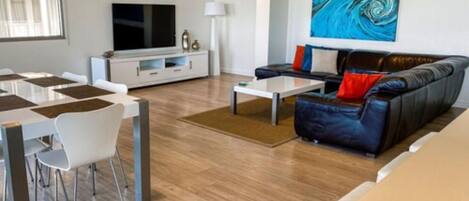 Un salon moderne avec un canapé, une table basse et un téléviseur.