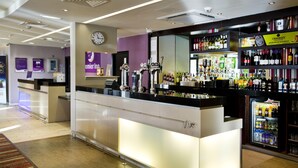 Un espace bar avec un comptoir, des étagères remplies de bouteilles et une horloge au mur.