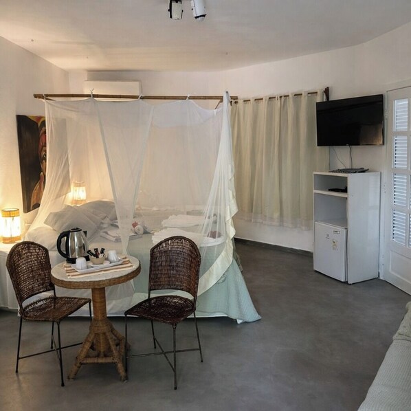 Una habitación con cama, televisión, una mesa con sillas y un pequeño armario.
