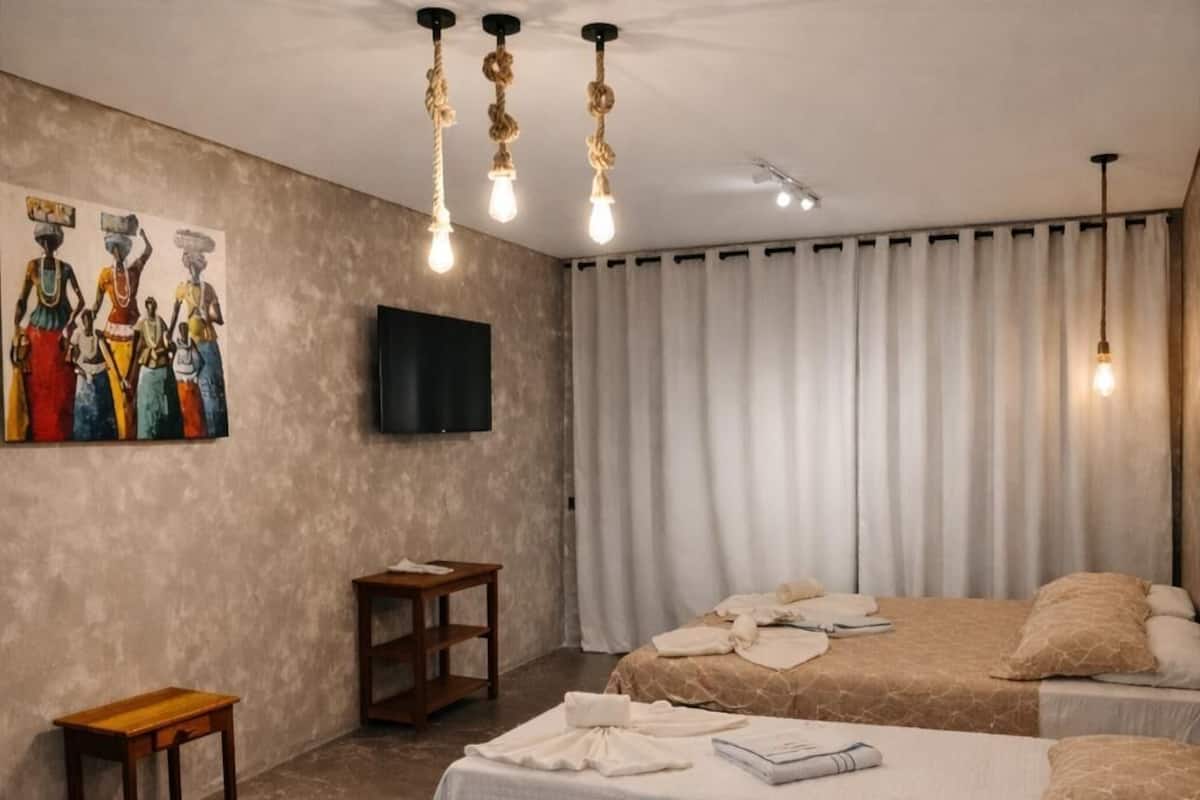 Un dormitorio con dos camas, televisión, un cuadro y una mesita.