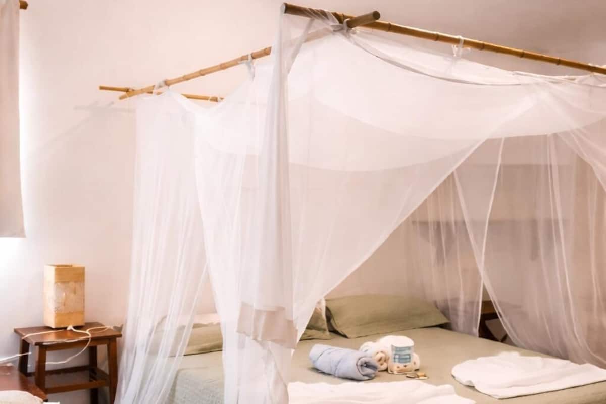 Una habitación con una cama bajo un dosel, una mesita de noche y un tocador.