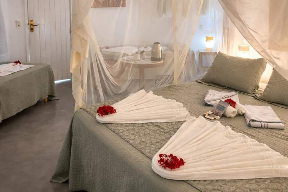 Una habitación con cama, mesita de noche, lámpara y una puerta.