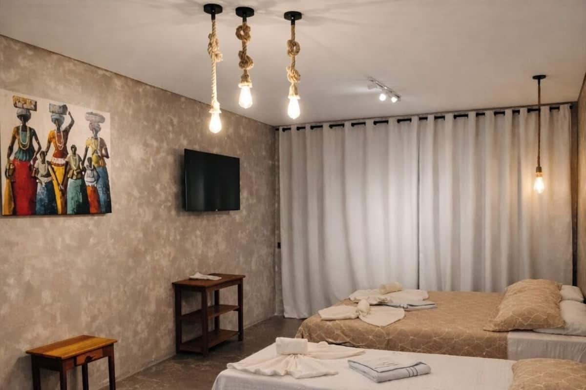 Una habitación de hotel moderna con una cama grande, una mesita, un televisor y un cuadro en la pared.