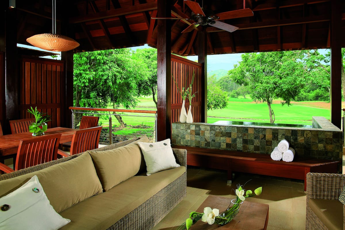 A covered outdoor seating area with a view of a golf course.