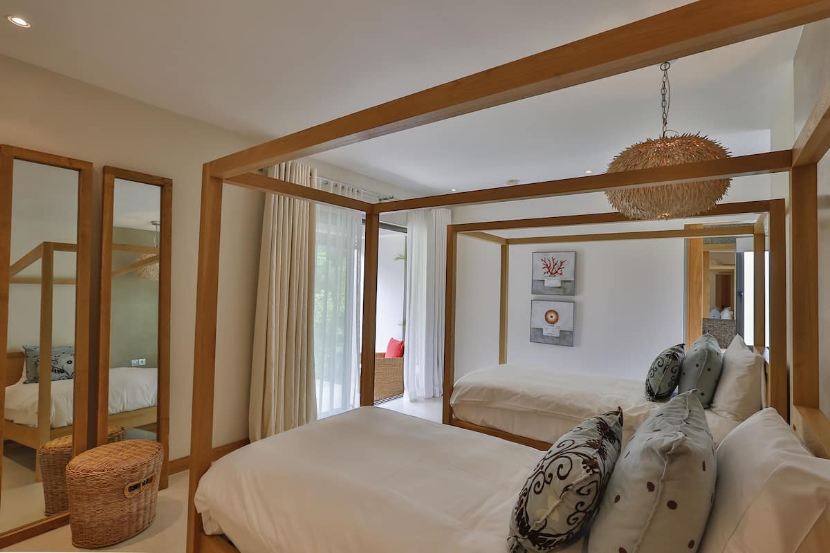 A bedroom with a large bed, a hanging light fixture, and a view of the outdoors through a glass door.