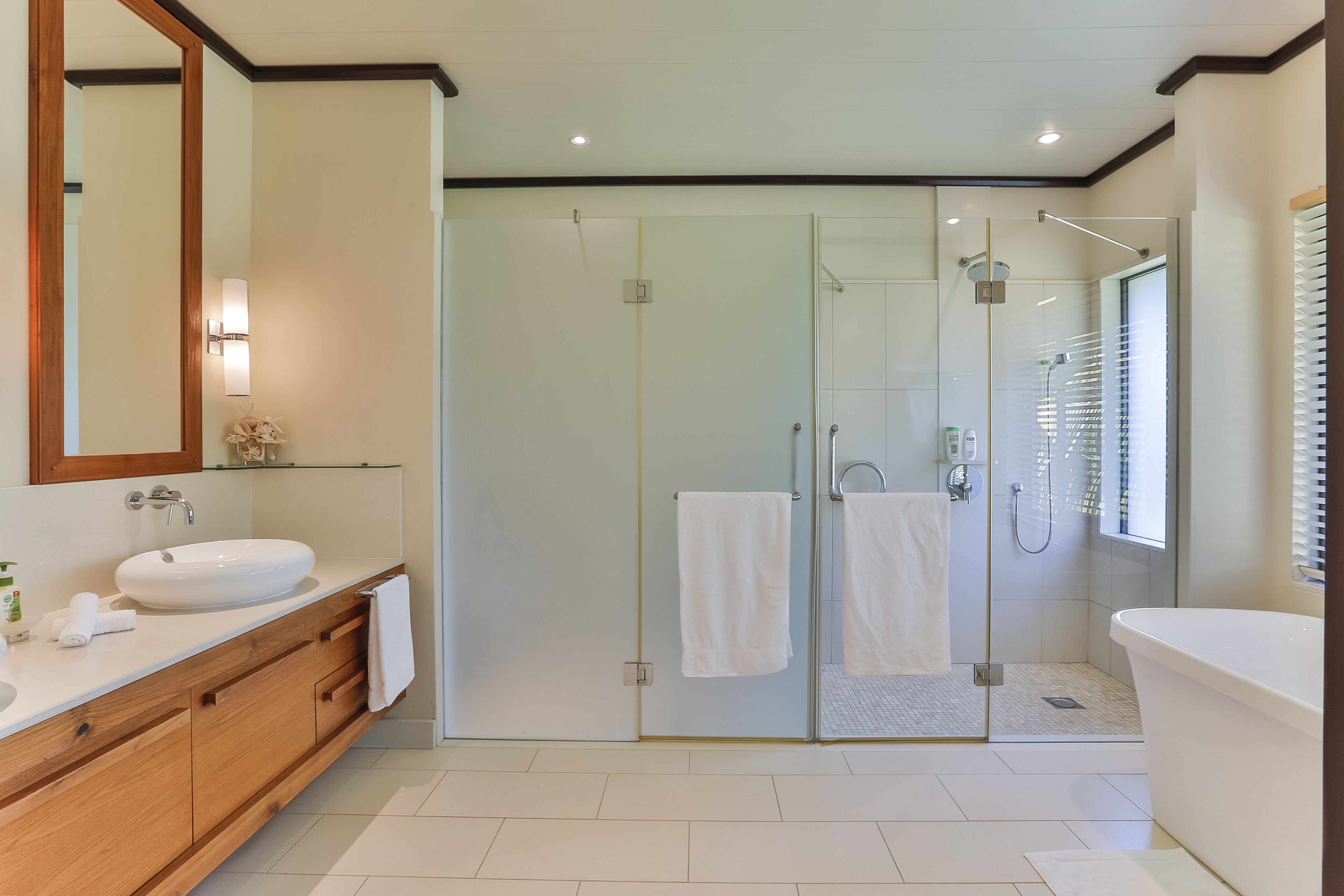 Une salle de bain moderne avec une douche à parois de verre, un grand miroir et un meuble-lavabo en bois.