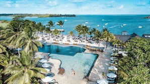 A resort with a large pool, palm trees, and a view of the ocean. - The Bay Club at Anahita (Grand River South East)