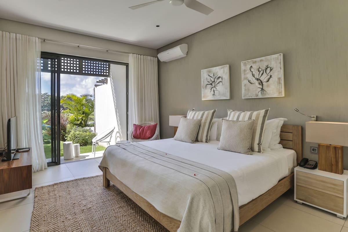 A modern bedroom with a large bed, a TV, and a balcony with curtains.