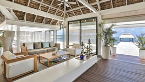 A spacious living area with a wooden ceiling, large windows, and a view of the sea. - The Bay Club at Anahita (Grand River South East)