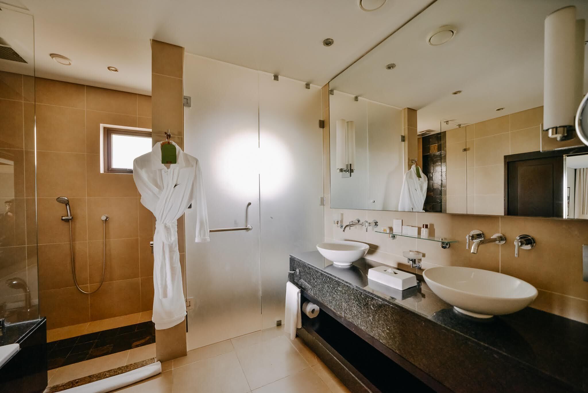 Une salle de bain moderne avec une douche à l’italienne, un grand miroir et un meuble-lavabo doté de deux vasques.