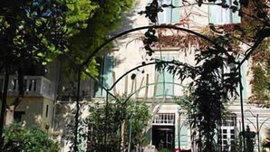 A building with a traditional architectural style, featuring a central entrance with a glass door and a small balcony. - Au St Roch Hotel et Jardin (Avignon)