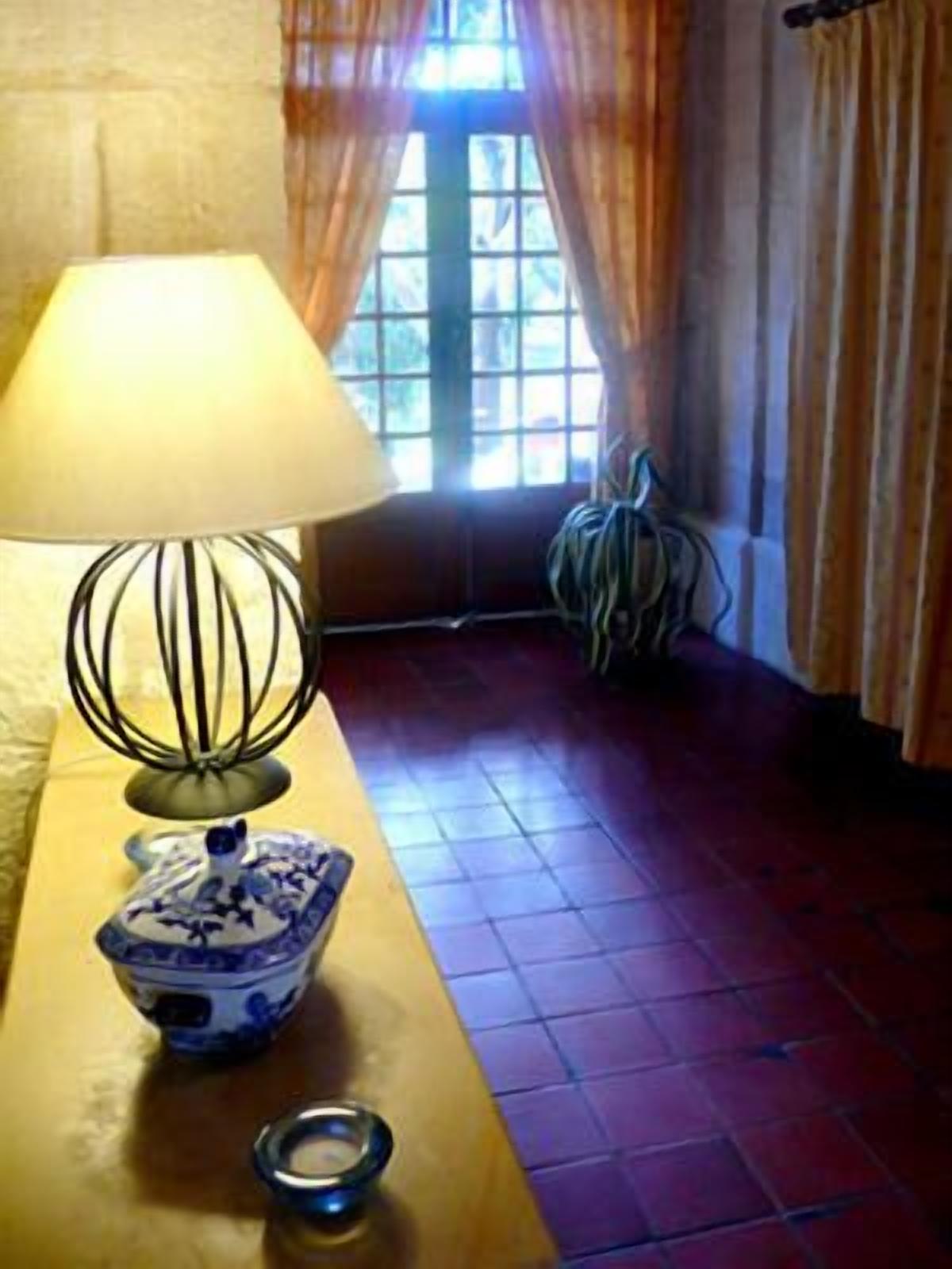 A room with a table lamp, a decorative bowl, and a window with curtains.