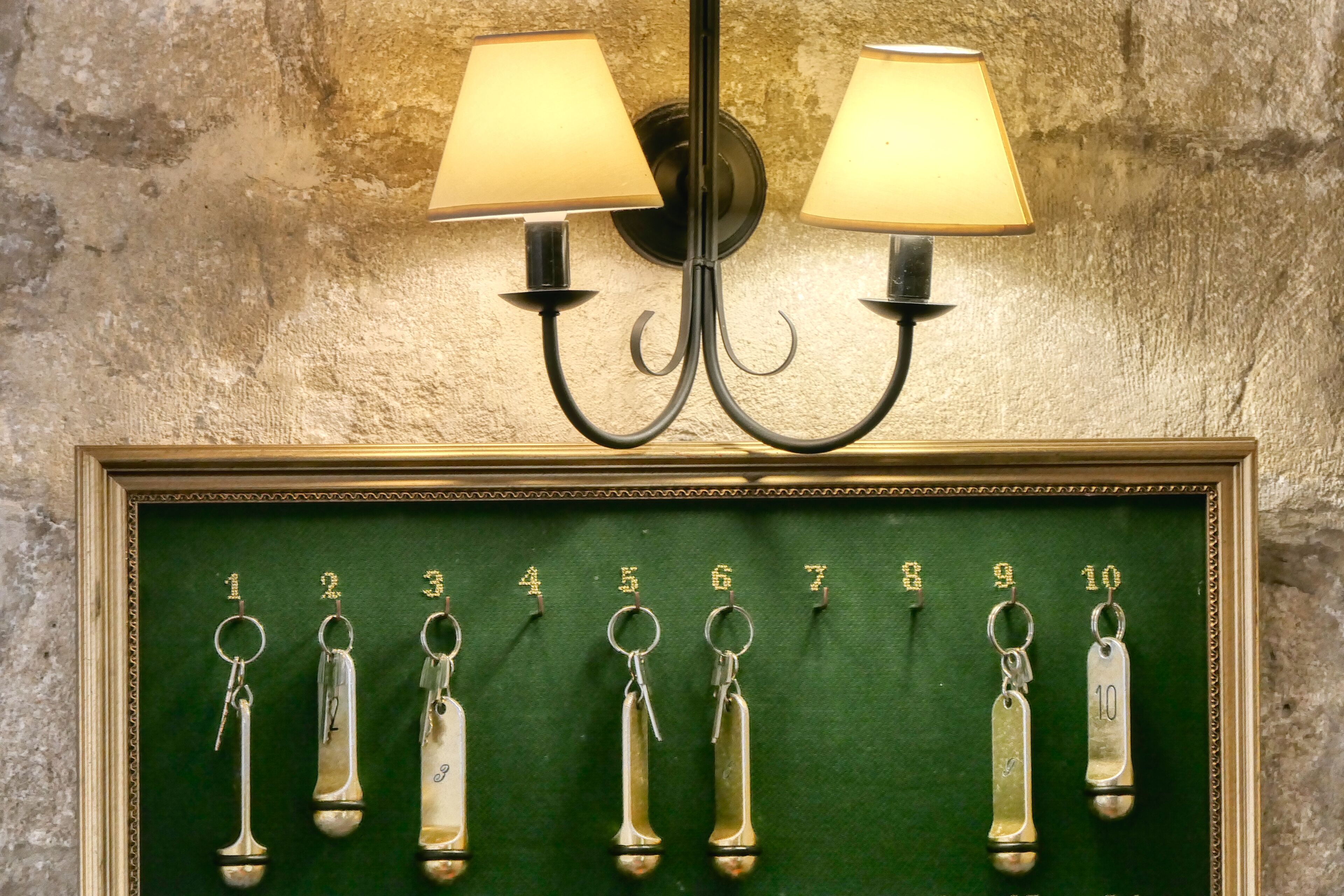 A wall-mounted lamp with two shades and a framed display of numbered keys.