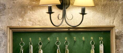 A wall-mounted lamp with two shades and a framed display of numbered keys.
