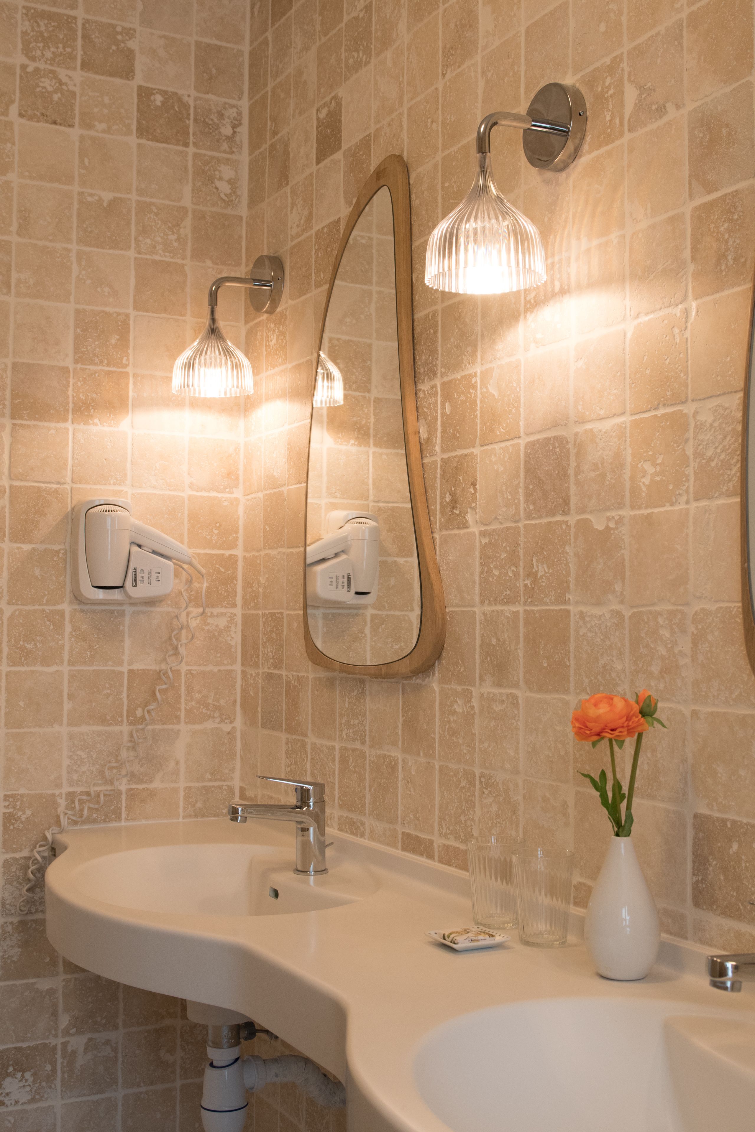 Een badkamer met een witte wastafel, een spiegel, een handdoekhouder en een douchekop.