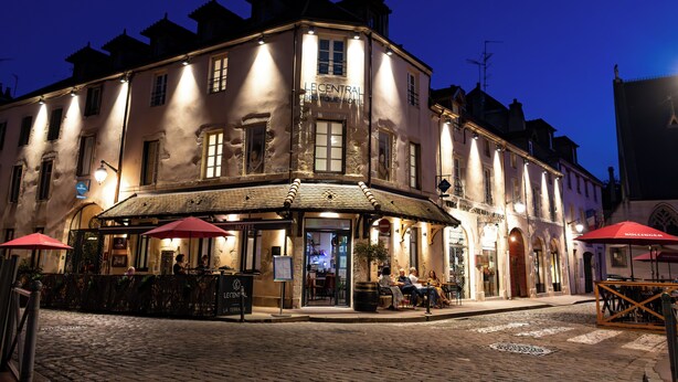 A historic building with a corner entrance, outdoor seating, and a sign for "Le Central Hotel." - Le Central Boutique Hôtel (Beaune)