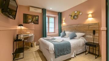 Une chambre à coucher comprenant un lit, une table de chevet, un bureau, une chaise et un téléviseur fixé au mur.