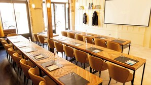 A conference room with long tables, chairs, and a projection screen. - Le Central Boutique Hôtel (Beaune)