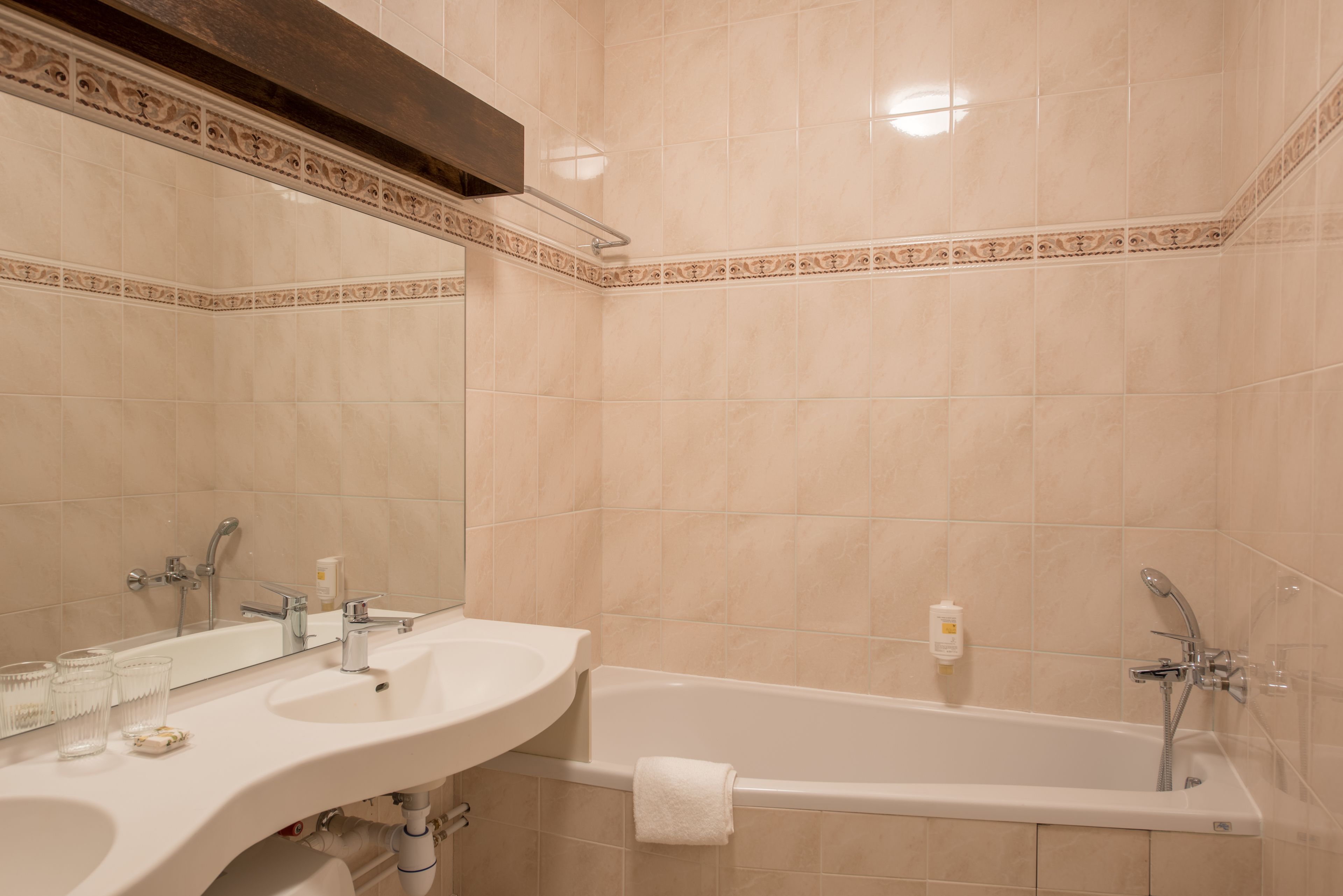A bathroom with two sinks, a bathtub, and a large mirror.