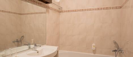 A bathroom with two sinks, a bathtub, and a large mirror.