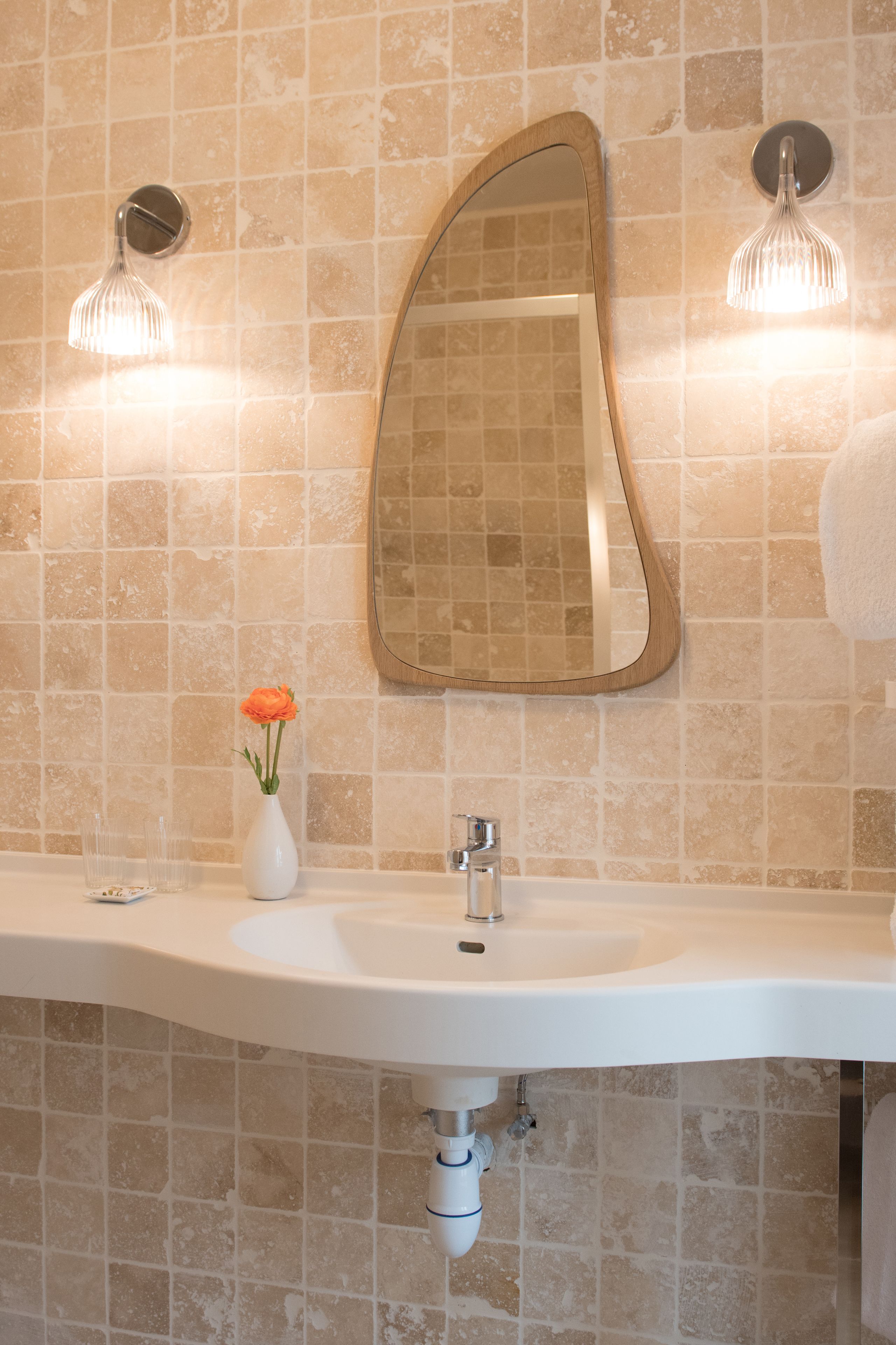 A bathroom with a white sink, a mirror, and two wall-mounted lights.