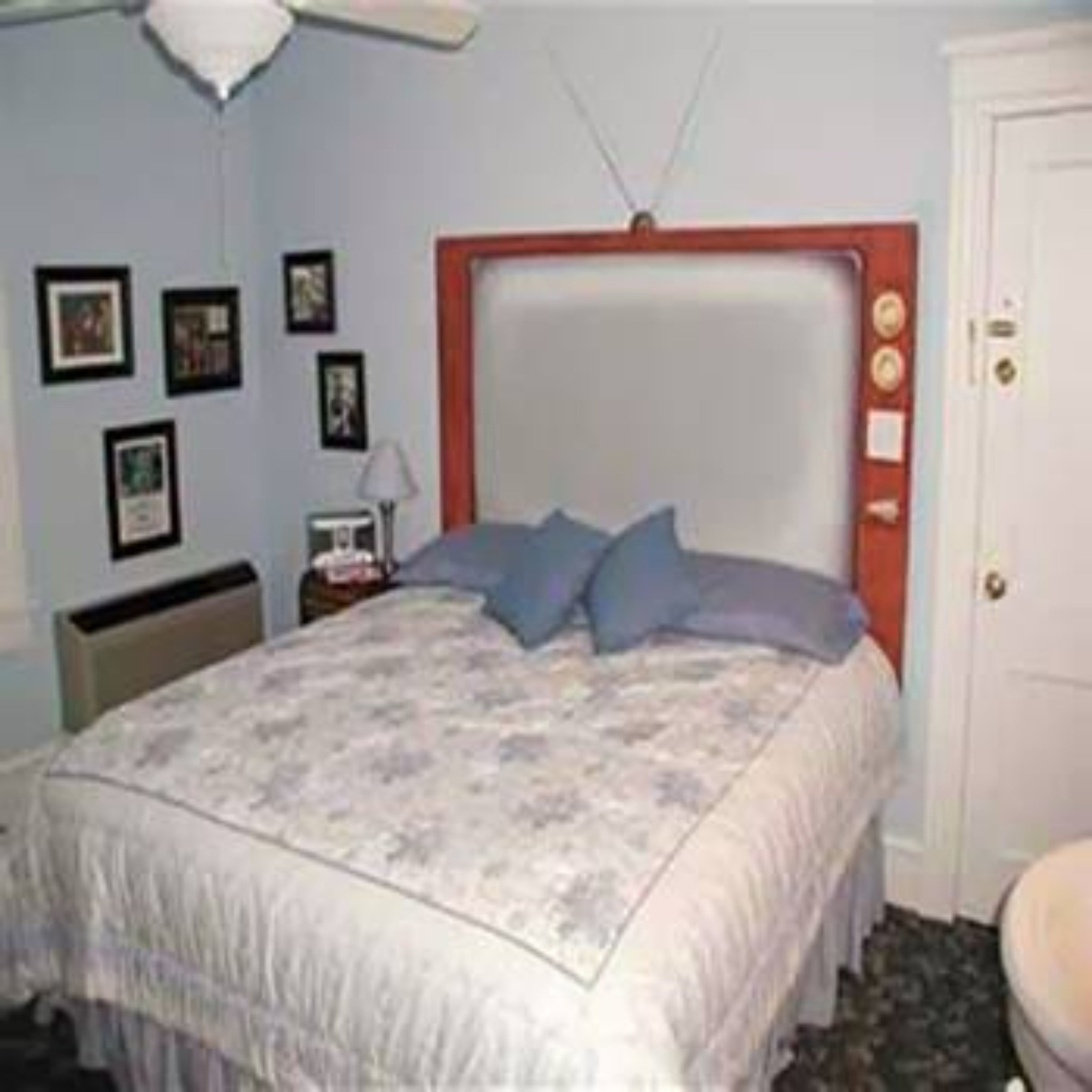 Une chambre à coucher avec un lit, une table de chevet, une lampe et une porte.
