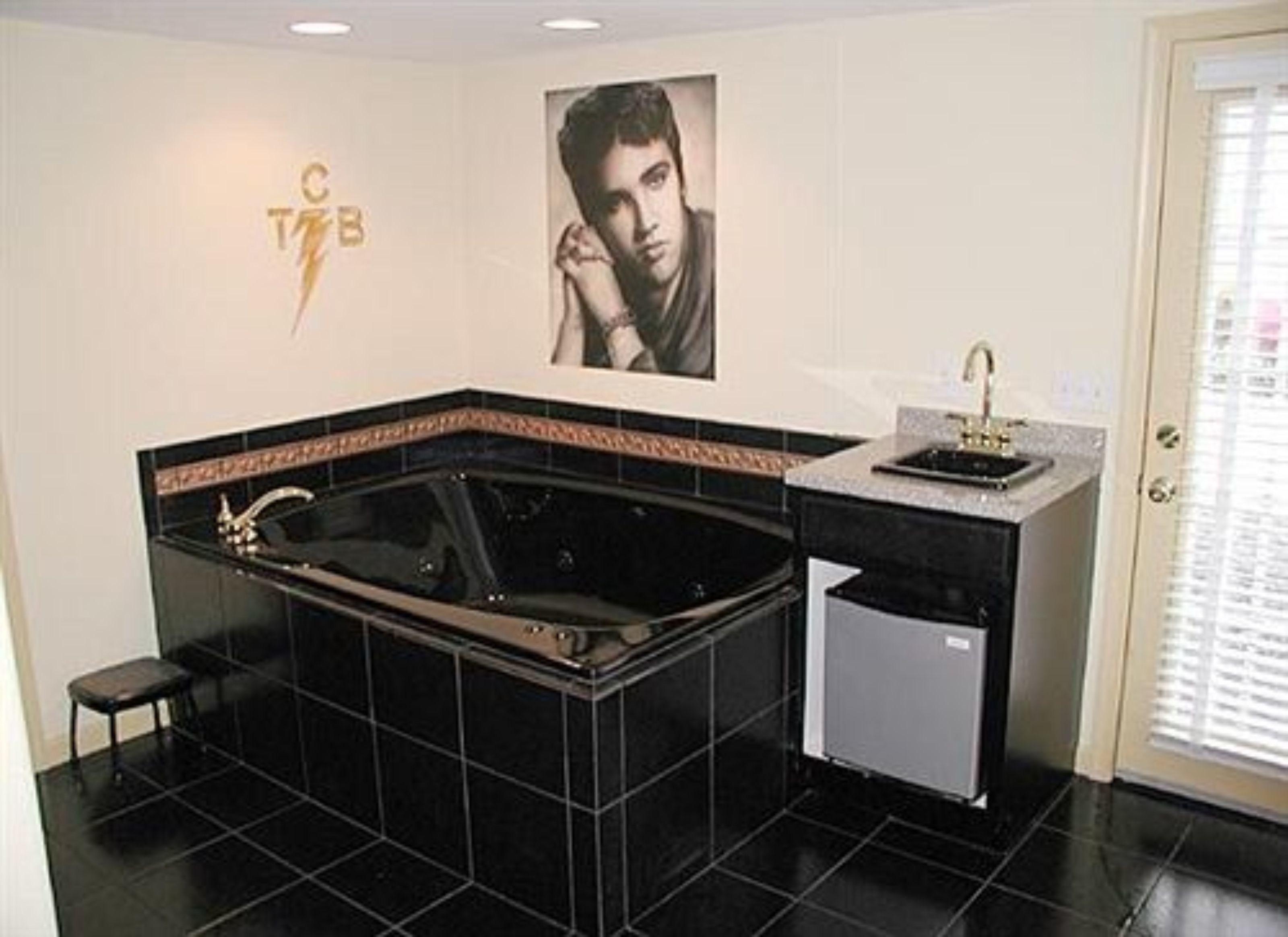 A bathroom with a black bathtub, a small sink, and a toilet. There is a towel rack and a mirror on the wall.