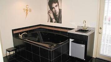 A bathroom with a black bathtub, a small sink, and a toilet. There is a towel rack and a mirror on the wall.