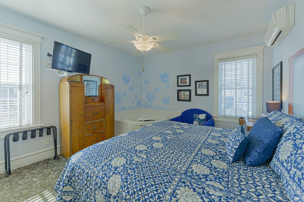 A bedroom with a bed, dresser, vanity, and a ceiling fan.