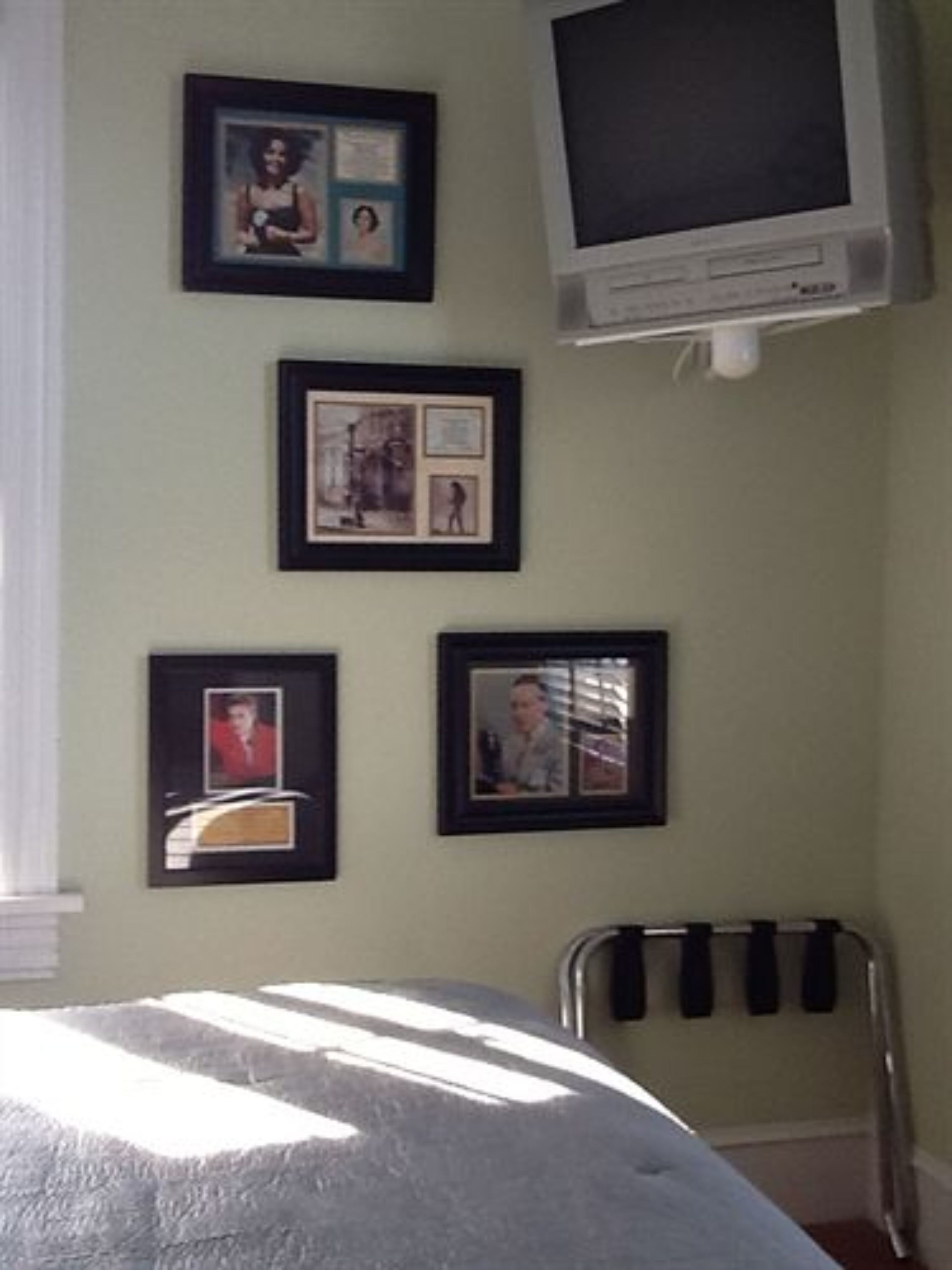 A bedroom with a bed, a TV, and framed pictures on the wall.