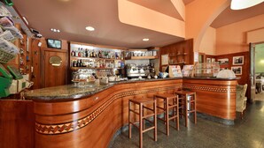 A bar area with a curved wooden counter, stools, and a variety of bottles and glasses on shelves. - Antica Locanda Luigina (Carrodano)