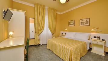 Ein Hotelzimmer mit Bett, Nachttischen, Schreibtisch, Stuhl, Fernseher und Vorhängen.