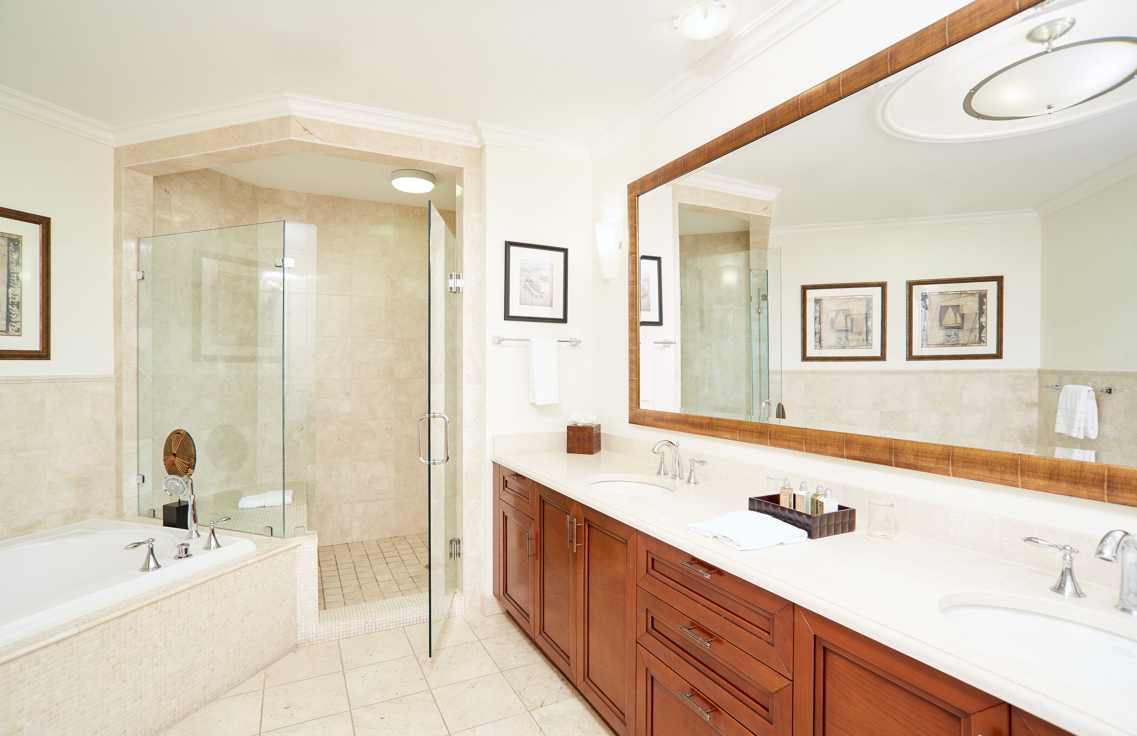 A modern bathroom with a glass-enclosed shower, a large mirror, and wooden cabinets.