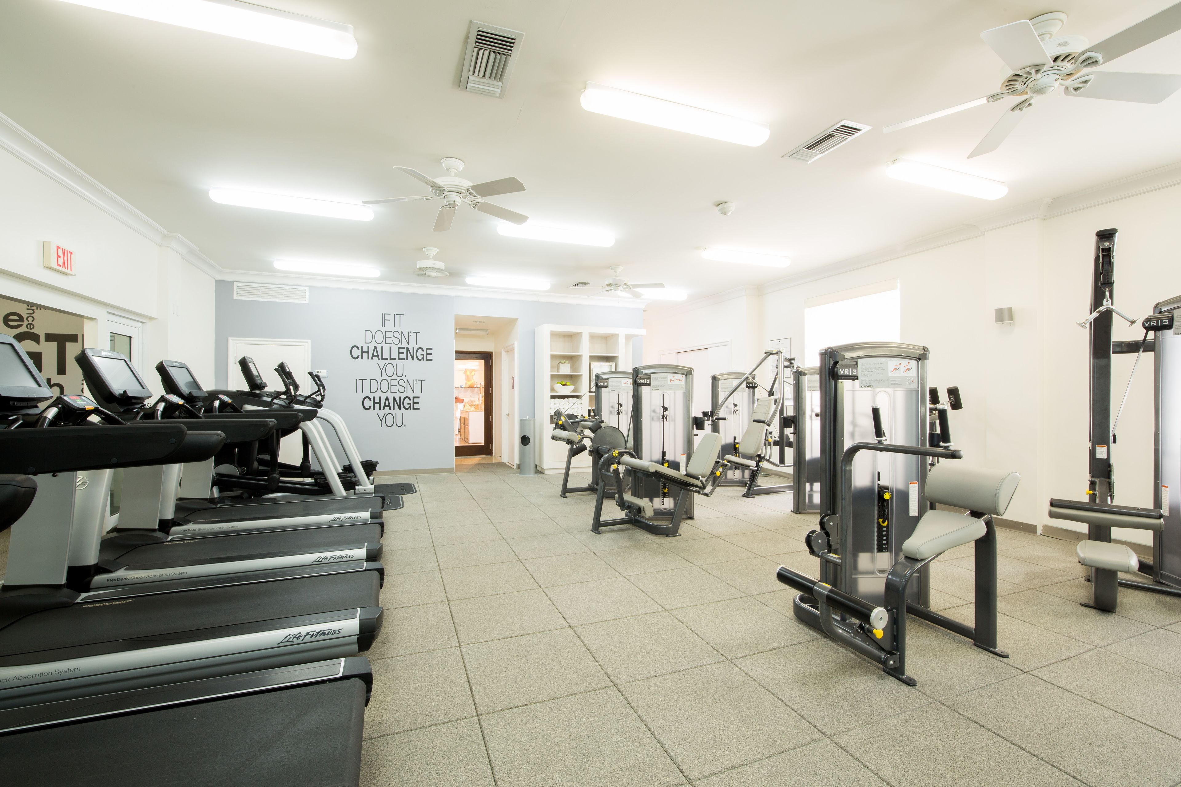 A gym with treadmills, weight machines, and a motivational quote on the wall.