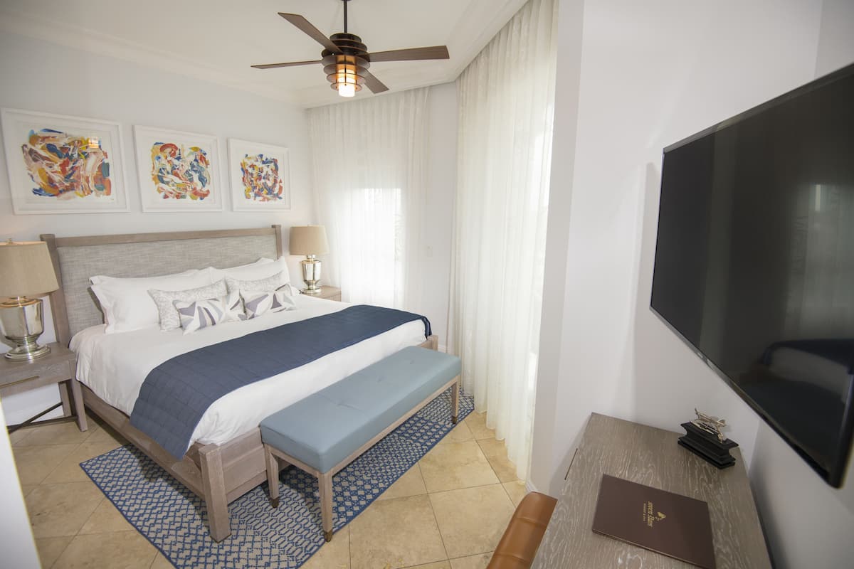 Quarto de hotel com cama, escrivaninha, televisão e obras de arte na parede.