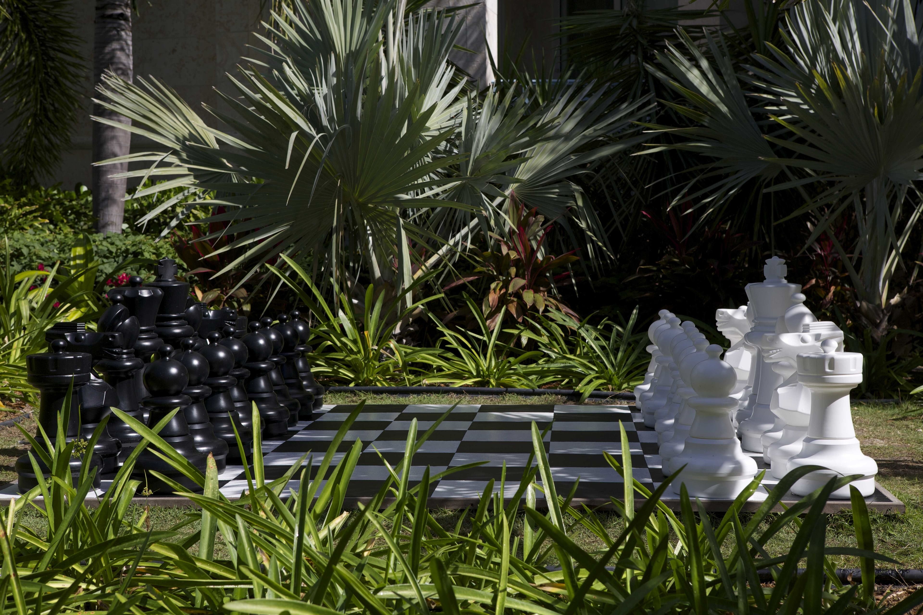A chessboard set outdoors surrounded by greenery.