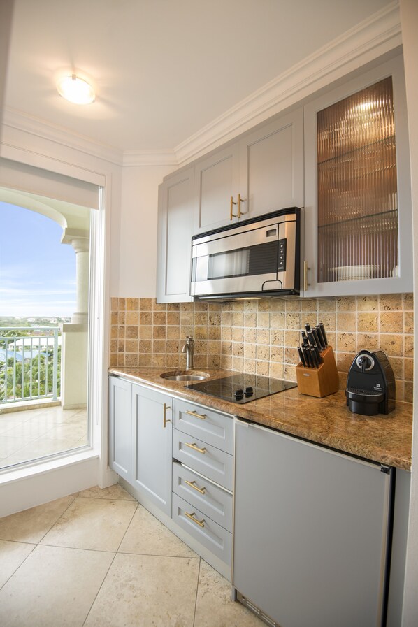 Una cocina con microondas integrado, un lavamanos y un bloque de cuchillos en la encimera.