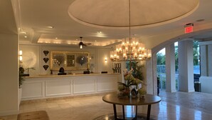 A lobby with a reception desk, a chandelier, a round table with a vase of flowers, and a ceiling fan. - Seven Stars Resort & Spa (Providenciales)